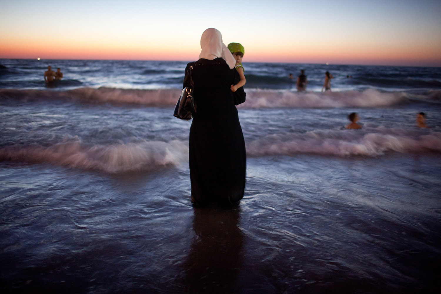 Aug. 21, 2012. A woman holds her baby as Palestinians enjoy a day at a beach during Eid al-Fitr, which marks the end of the holy month of Ramadan in Tel Aviv.