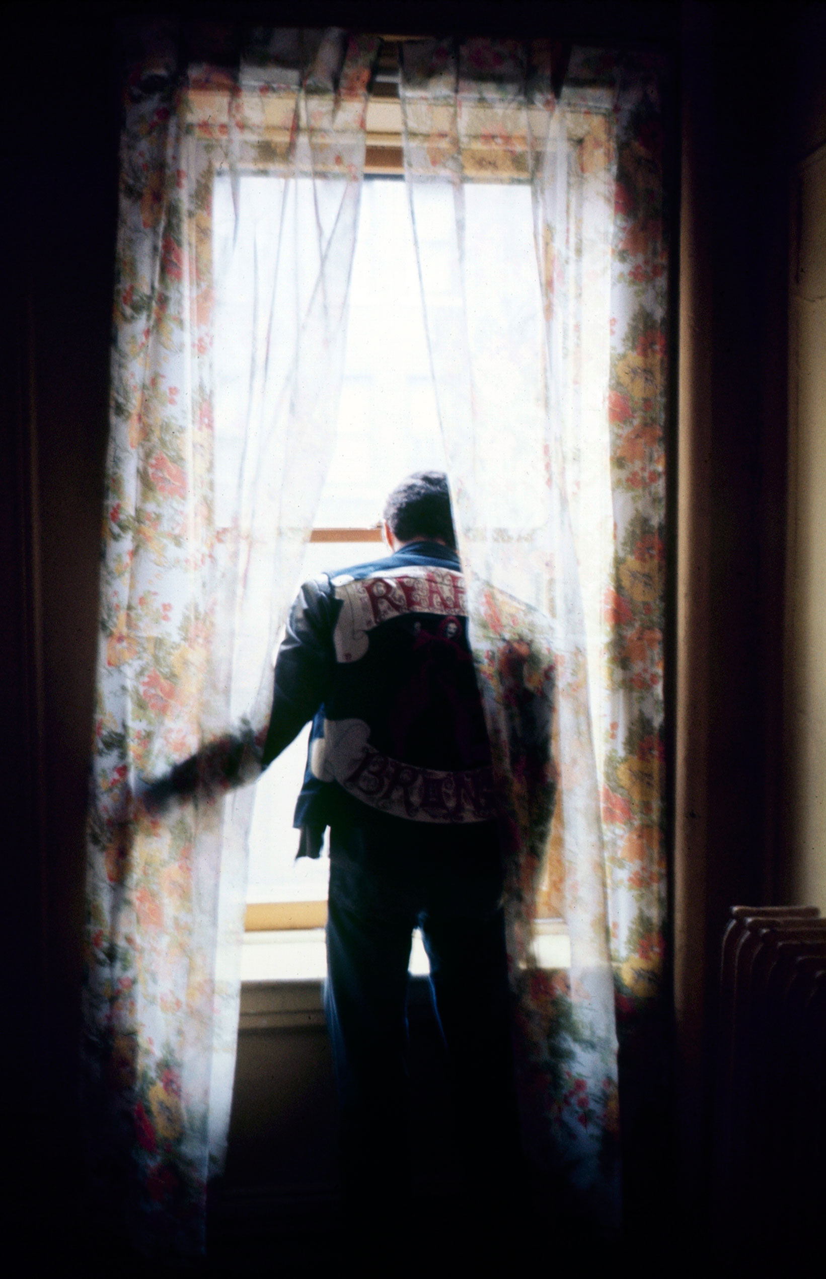 Eddie Cuevas, president of the Reapers street gang, peers out a window in the South Bronx, 1972.