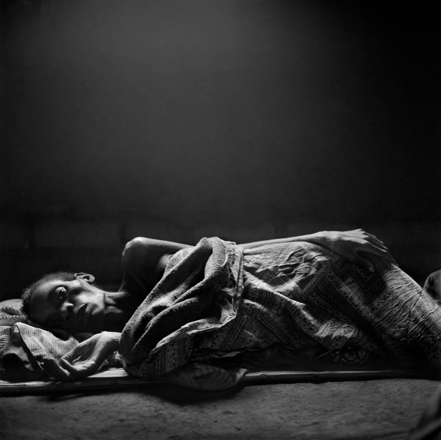 1997: Kristen Ashburn
                              
                              Stella Forty (42 yrs) lies dying of AIDS on the floor of her home. When she died in Nov 2006, her husband was left to care for their five children. Nsanje, Malawi.
                               I attended the Eddie Adams Workshop as a student at New York University and was pretty naive and eager. The workshop was my first introduction to the photography community. It was inspiring to meet the professionals who donated their time at the workshop. You could tell that everyone gave 100% of themselves and truly cared about the student participants.
                              
                              Eddie was still alive at that time. His tribute to photographers killed while covering stories gave me goose bumps. It was then that I began to understand the bond between photographers. I also remember standing there thinking about the journeys of those who died and wondering where mine would take me. I suppose that was also my first real lesson in photojournalism—no one ever knows what’s in store for them or how much they will sacrifice while working.
                              
                              Eddie’s tribute to those lost could not be any more relevant than today as we continue to lose exceptional photographers and friends.