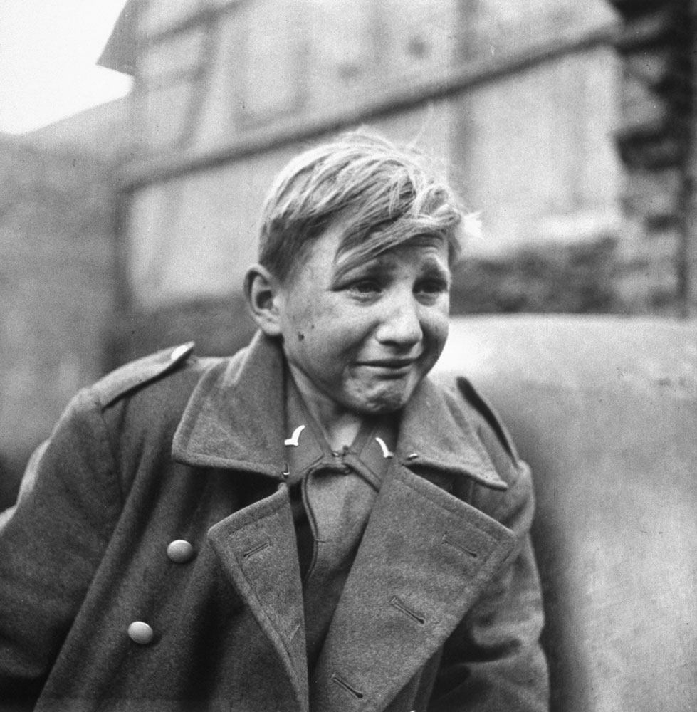 A fearful 15-year-old German Luftwaffe anti-aircraft crew member weeps after being taken prisoner by American forces during the drive into Germany in 1945.