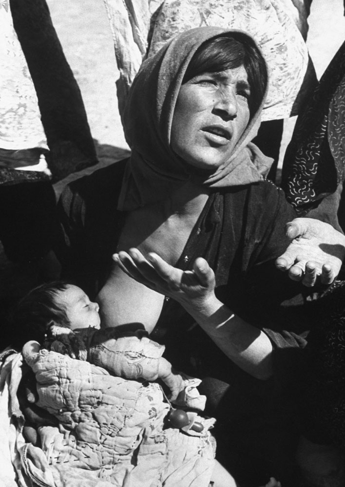 A woman breastfeeds a baby amid the ruins in the aftermath of a September 1962 earthquake in Iran.