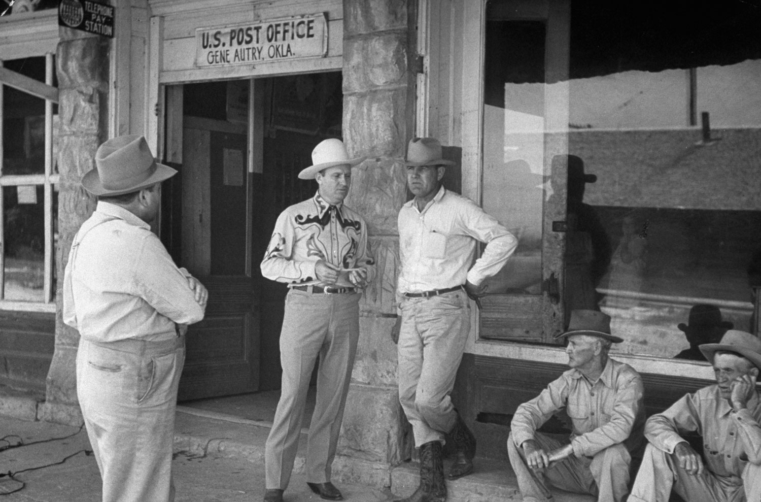 Singing cowboy Gene Autry (second from left) stands outside the post office in an Oklahoma town named for him, 1948.