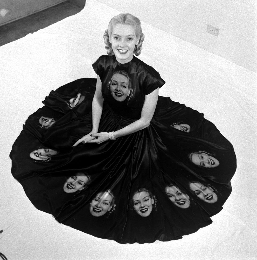 Surrounded by a skirt full of her own pretty face, model Norma Richter shows off dress made especially to demonstrate photographic fabrics.
