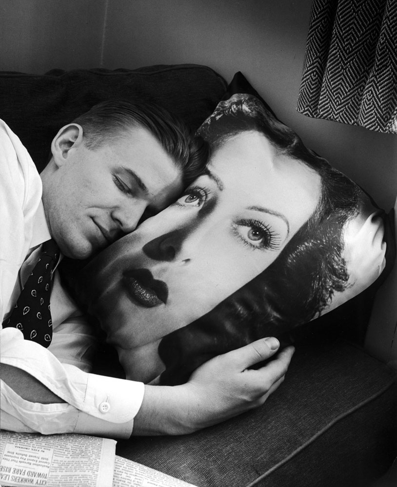 Hedy Lamarr pillow is cuddled by a Lamarr fan. Hedy's face is very lifelike and about twice life size.