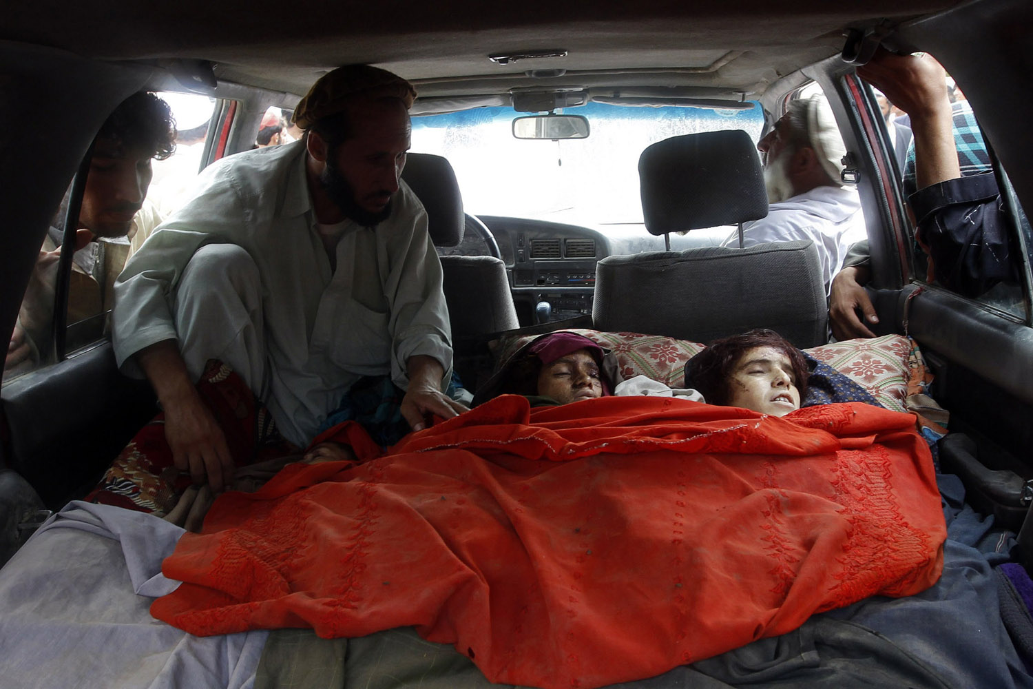 Sept. 16, 2012. Afghan villagers look at the bodies of women killed by NATO air strikes in Laghman province.