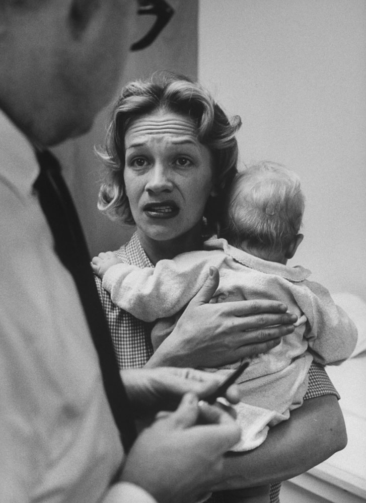 Pediatrician Dr. Ralph Shugart confers with a worried mother of a baby that has been crying for hours, 1963. He decided to give them both a sedative.