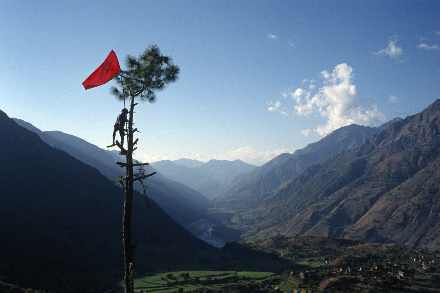2000: Tomas van HoutryveNabin Pun, a Maoist rebel soldier of the People's Liberation Army, raises the communist flag from a tree above the village of Rukumkot, Nepal on Feb. 11, 2005.
                              “Nick Ut and Kim Phuc gave presentations at the Eddie Adams workshop I attended. What struck me during their talks was how Nick had managed to take the picture of Kim fleeing from the napalm attack, and as soon as he had the photo, he carried her to the hospital. He took one of the most important and iconic photos of the Vietnam War, yet he didn't lose sight of his basic humanity to help out a little girl in pain. In a very tough conflict situation he played it just right. It was a lesson from a rare story outside the viewfinder—of how photojournalists should behave. It stuck with me. Don't miss your shot, and don't let it distract you from your moral duties to fellow human beings.”