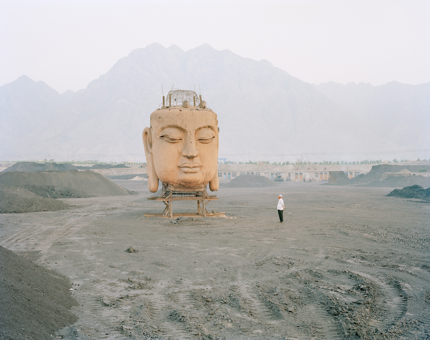 image: A giant Buddha's face in a coal yard, Ningxia province.