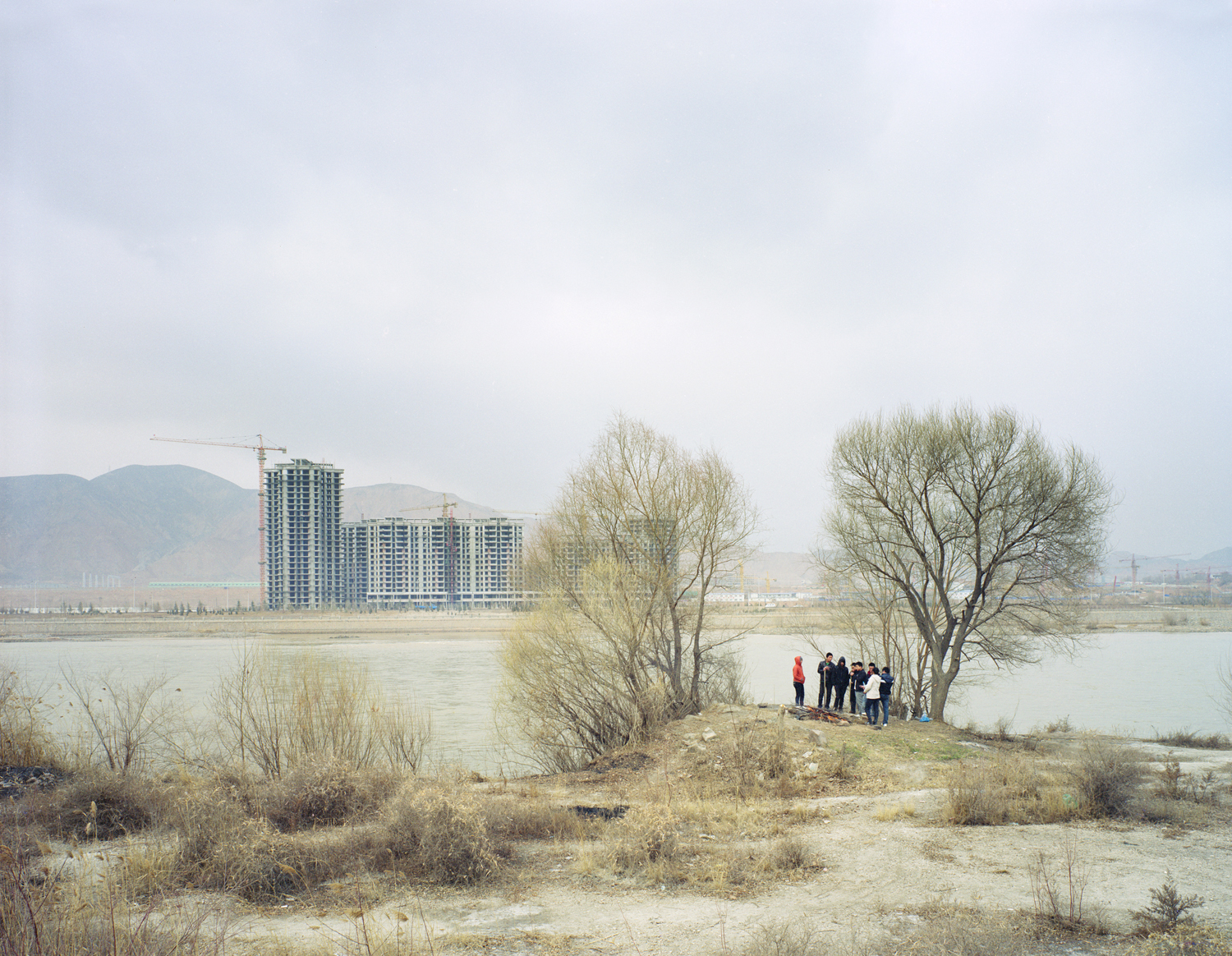 image: Young people gathered around a fire by the river, Gansu province.