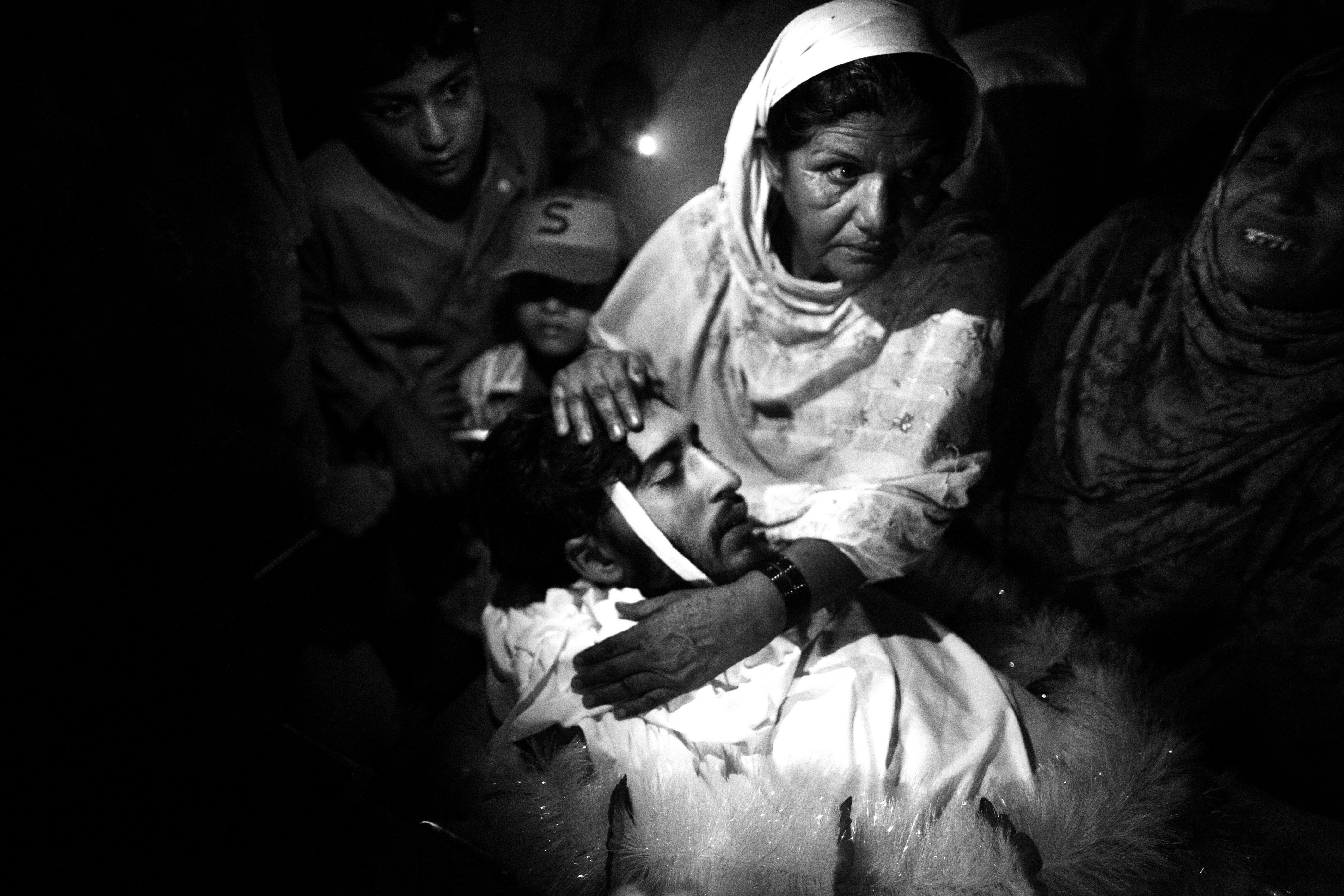 The dead body of a 20-year-old man in Karachi who was assassinated by unknown gunmen. His mother and the rest of the family gathered around his body in the Abbasi Shaheed Hospital, to carry him home for the funeral.
                              September 2010.