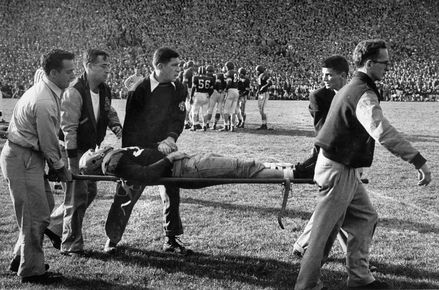 A player is carried from the field with a broken collar bone during a 1952 Notre Dame-Michigan game.