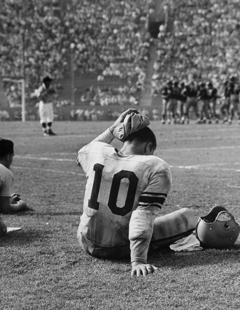 Minnesota University's Paul Giel, exhausted after a 67-yard run which set up Minnesota's only touchdown against USC, puts an ice pack on his head, 1953.