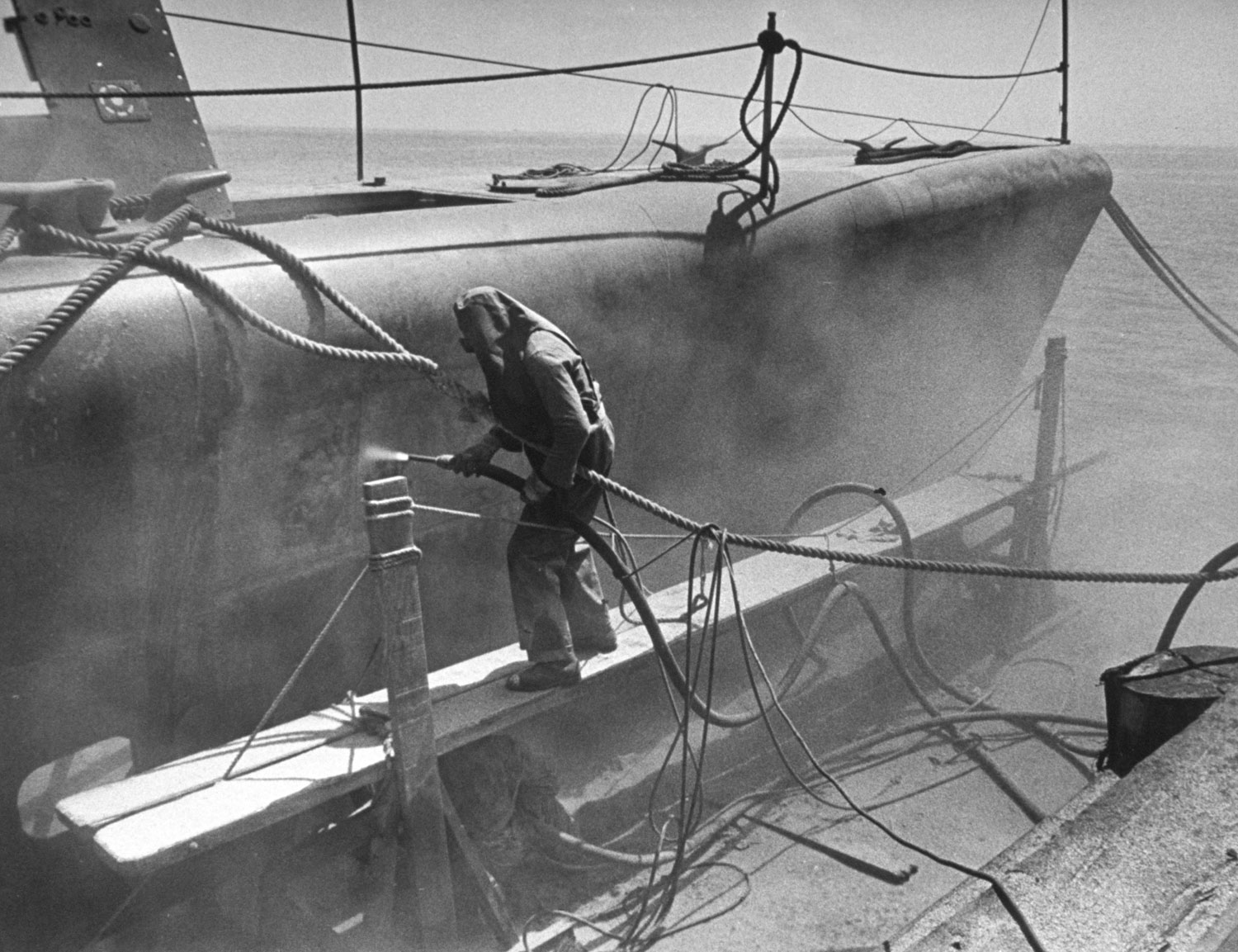 Navy workman sandblasts radioactive paint off the side of submarine contaminated during the Baker nuclear test in July 1946.