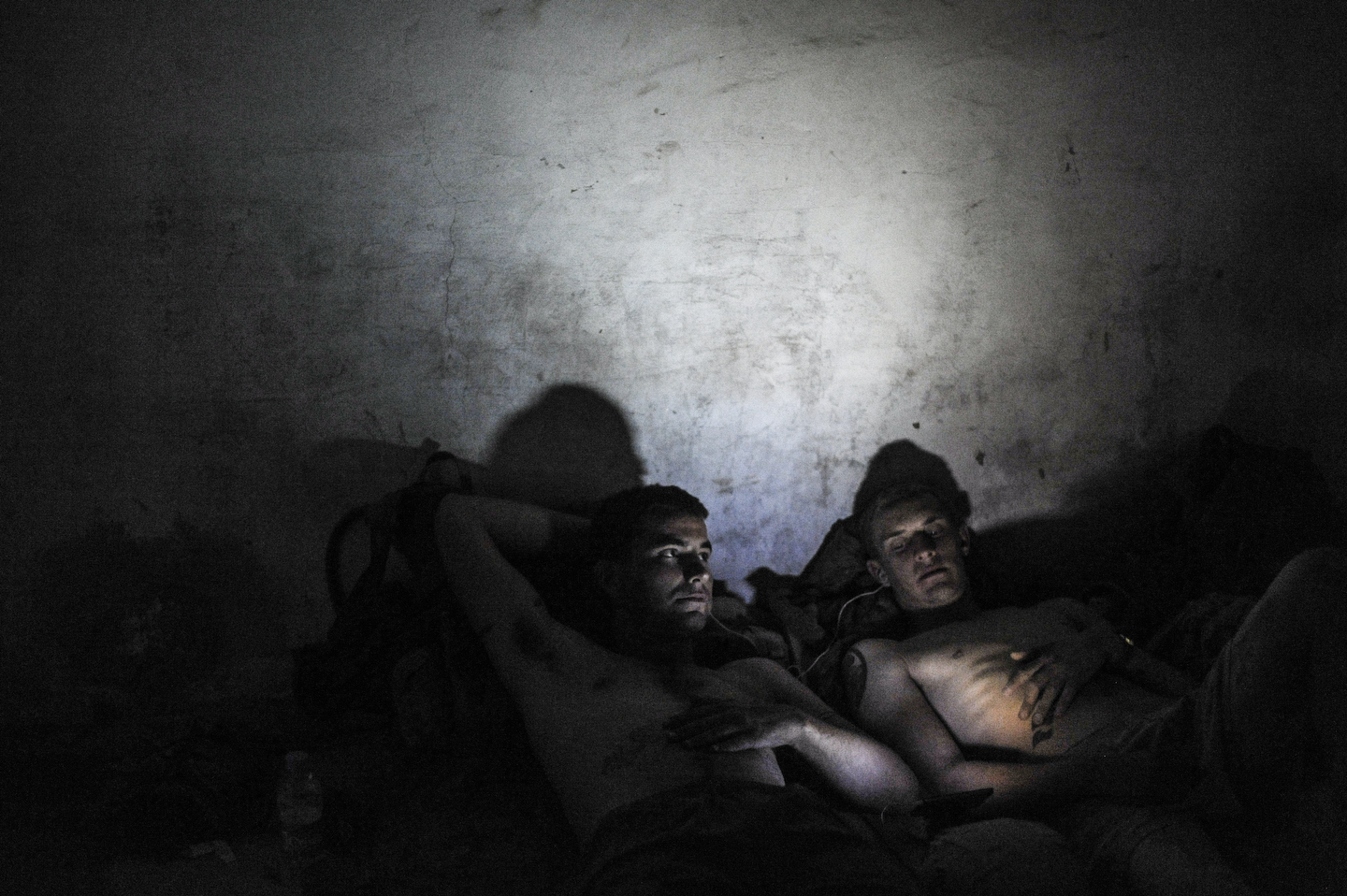 Afghanistan, 2009. Two Marines talk quietly at COP Sharp before going to bed in Helmand, Afghanistan. The Marine on the left, Corporal Matt Kaiser, had nearly been killed by a buried bomb earlier that day. He was sweeping the road with a minesweeper when the dirt exploded right in front of him.  He staggered back saying,  God, I'm still here,  and clutching his ears. He laughed and for the rest of the day, couldn't hear much and talked way too loud.  It was the second time in just a few weeks he'd nearly been killed by a bomb.