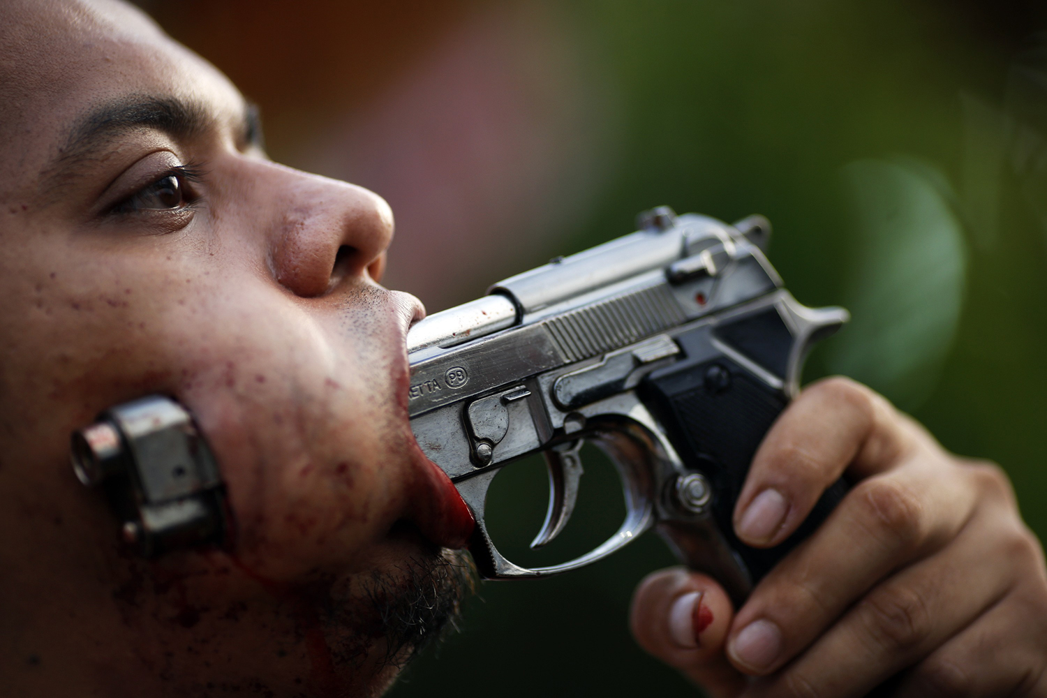 Image: Oct. 19, 2012. A devotee of the Ban Tha Rua Chinese shrine with a gun pierced through his cheek takes part in a procession celebrating the annual vegetarian festival in Phuket, Thailand. The festival celebrates the local Chinese community's belief that abstinence from meat and various stimulants during the ninth lunar month of the Chinese calendar will help them obtain good health and peace of mind.