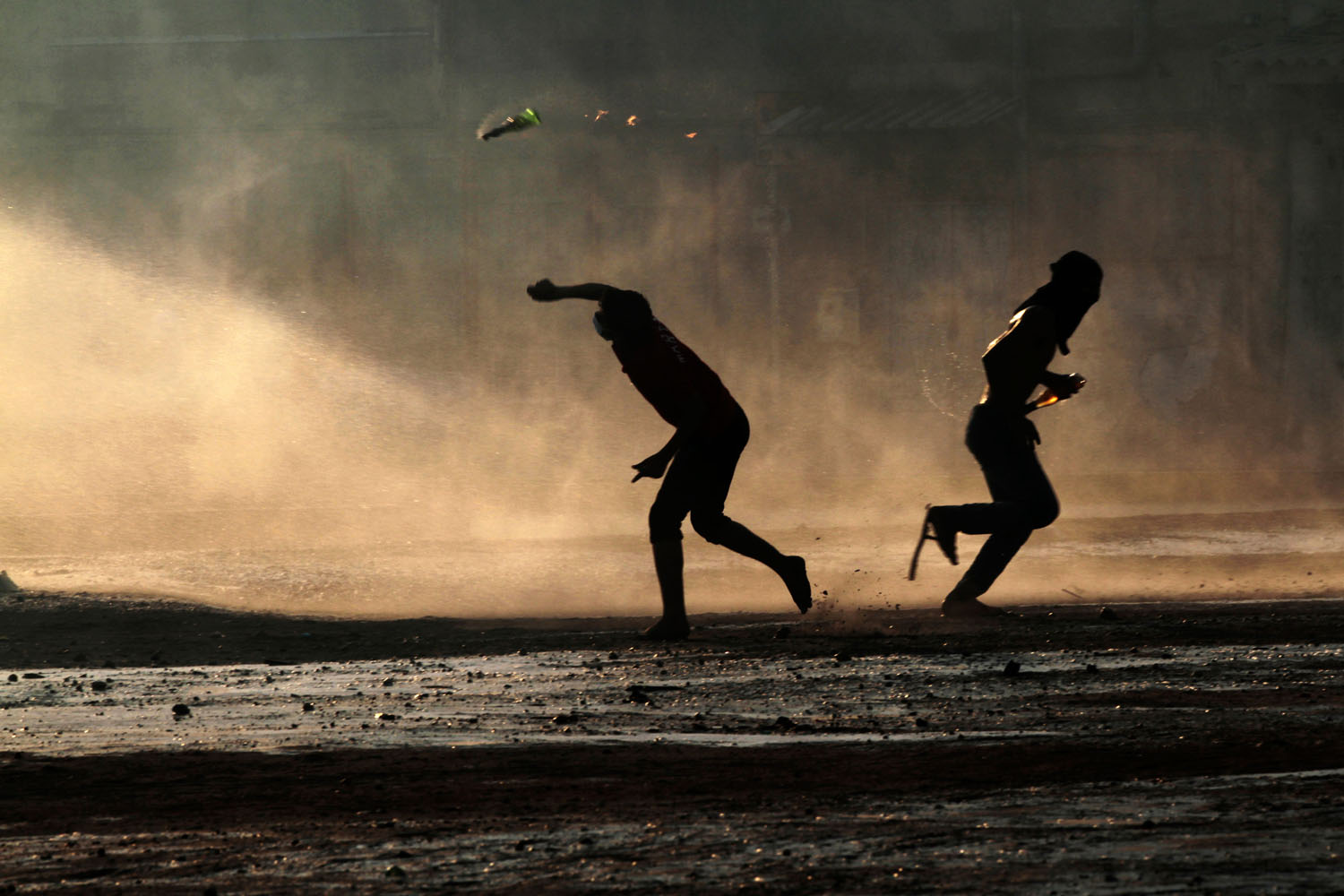Oct. 5, 2012. Bahraini anti-government protesters, masked against tear gas, throw petrol bombs at a police water cannon truck during clashes with riot police in Sanabis, Bahrain.