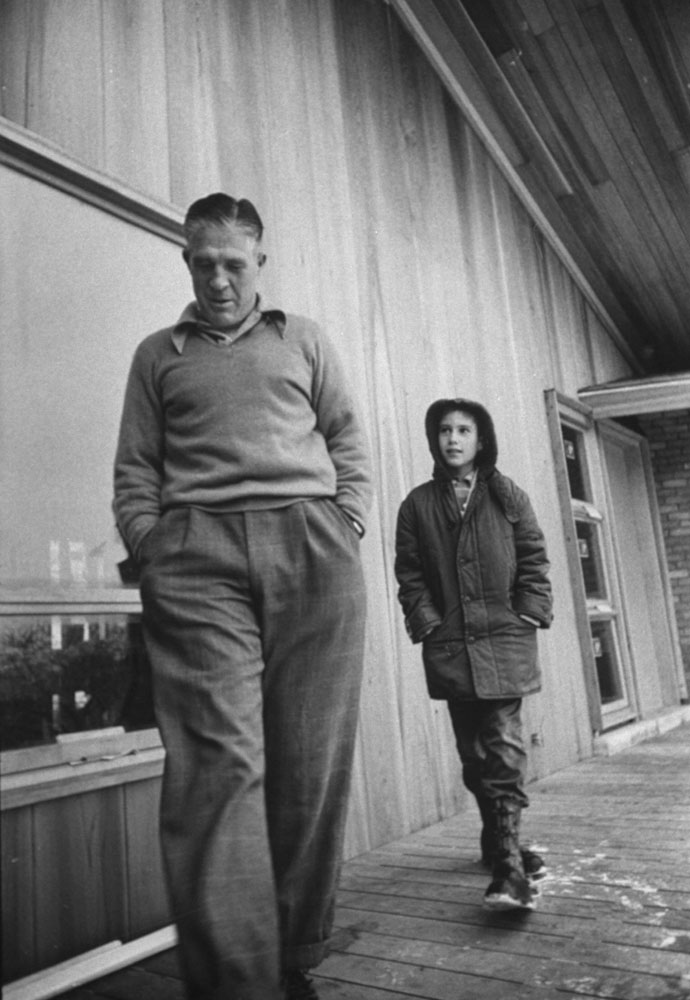 With 'Mitt,' 10, youngest of Romney children, [George Romney] inspects house at Bloomfield Hills which he and his wife designed.