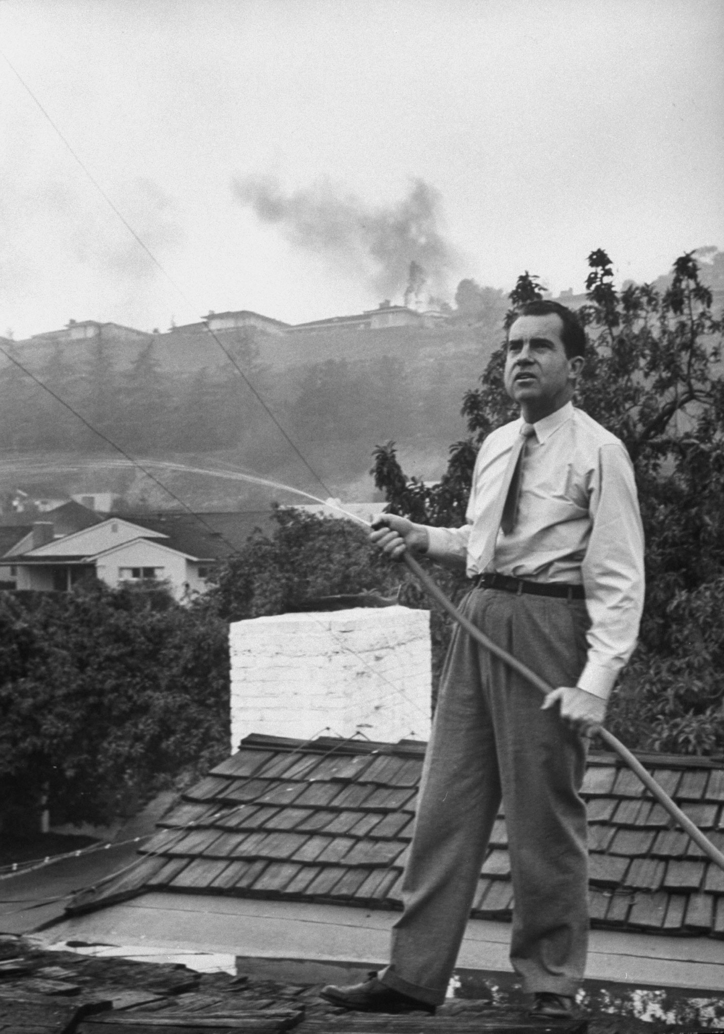 Senator Richard Nixon on the roof of his home in Los Angeles, trying to douse fires caused by a brush blaze, 1961.