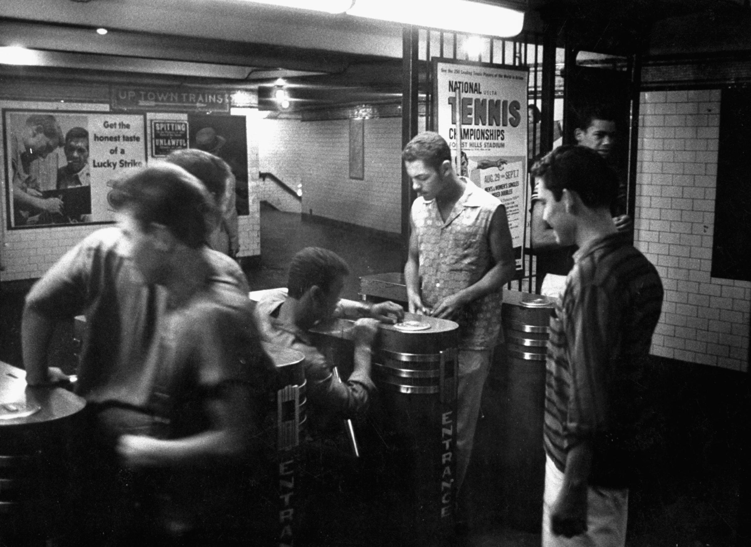Teenagers trying to work the subway turnstiles with slugs instead of tokens, 1958.
