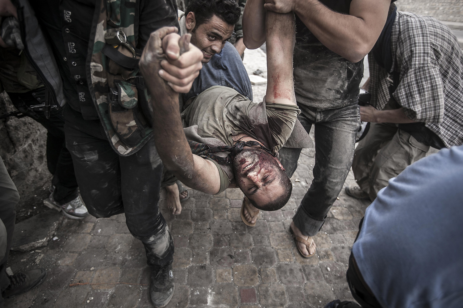 Image: Oct. 20, 2012. A Free Syrian Army fighters carry a civilian away from the line of fire after he was shot twice by a Syrian army sniper in Aleppo, Syria.