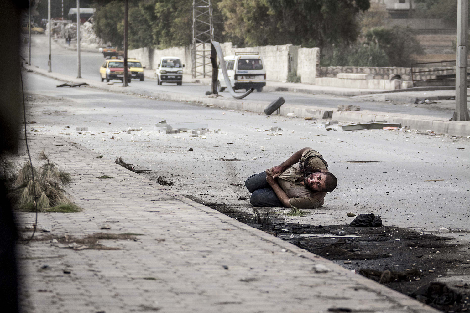Image: Oct. 20, 2012. A wounded Syrian civilian lies in the street with a shot to his stomach as he tries to escape the line-of-fire after he was targeted by a Syrian army sniper in Aleppo, Syria.