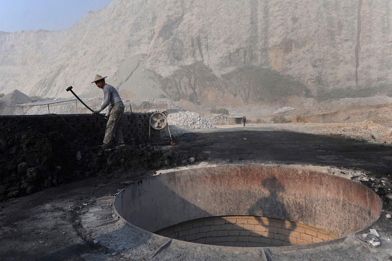 Oct.12, 2012. A worker smashes coal as he prepares to burn limestone at a nearby furnace inside a limestone mine in Quzhou, Zhejiang province, China.