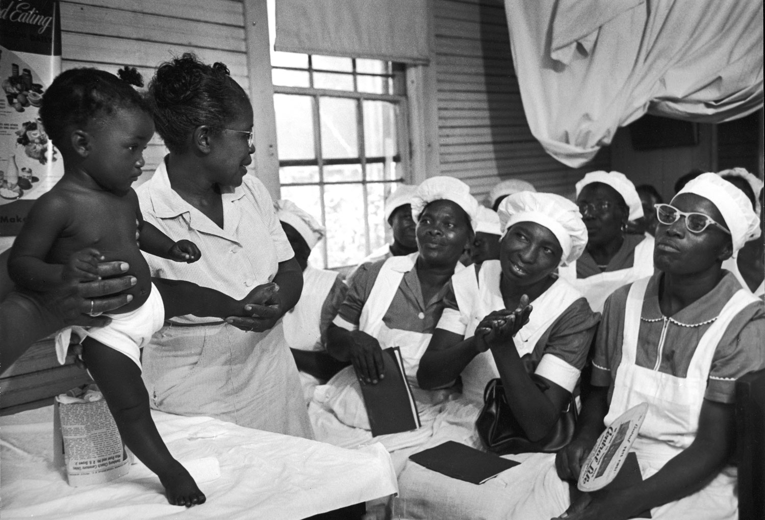 Caption from LIFE. Teaching a midwife class, Maude shows how to examine a baby for abnormalities. She conducts some 84 classes, helps coach about 12 new midwives each year. ...