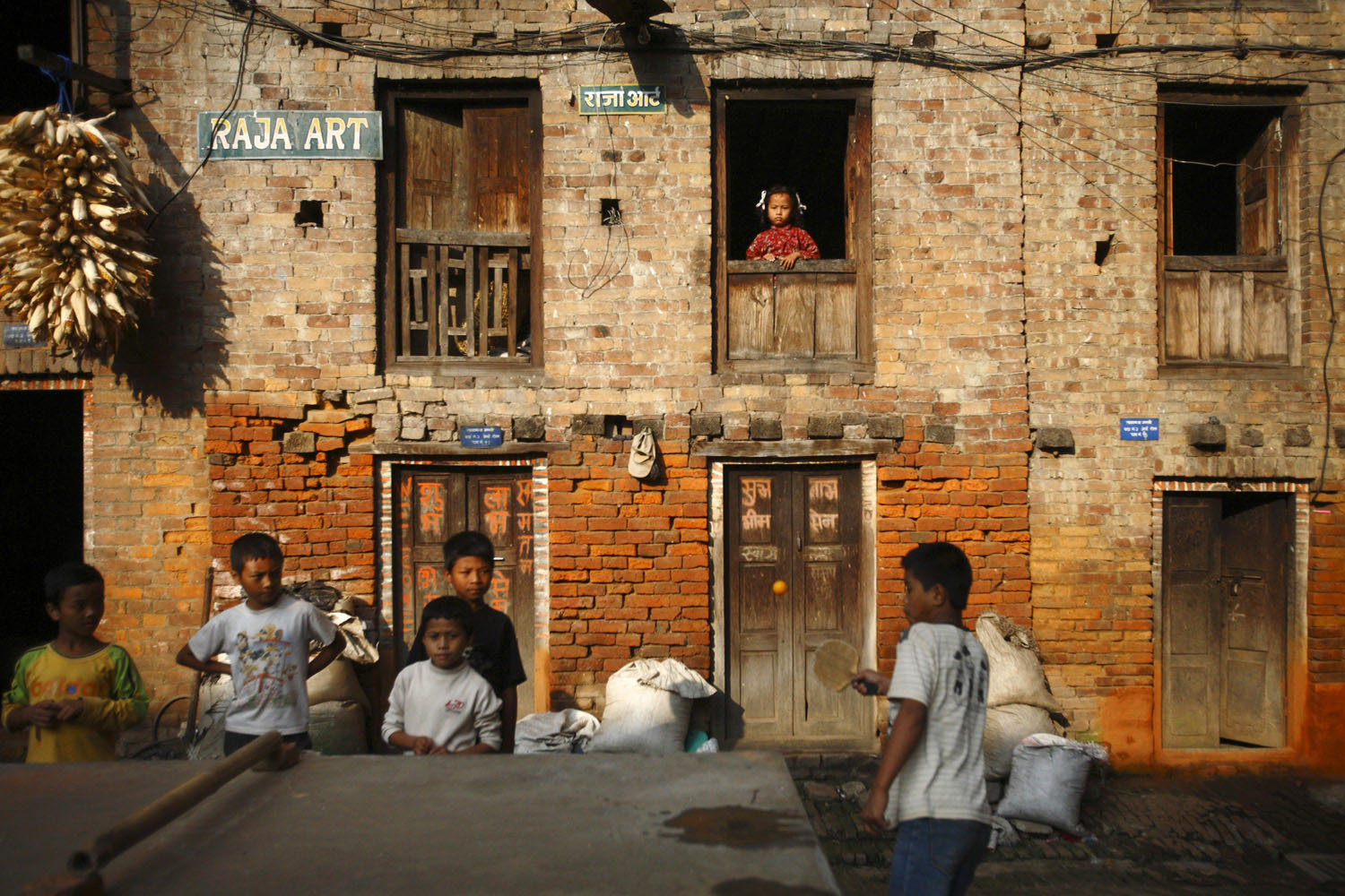 Oct. 8, 2012. A girl looks out from the window of her home as children play ping-pong outside in the ancient Nepalese city of Bhaktapur.