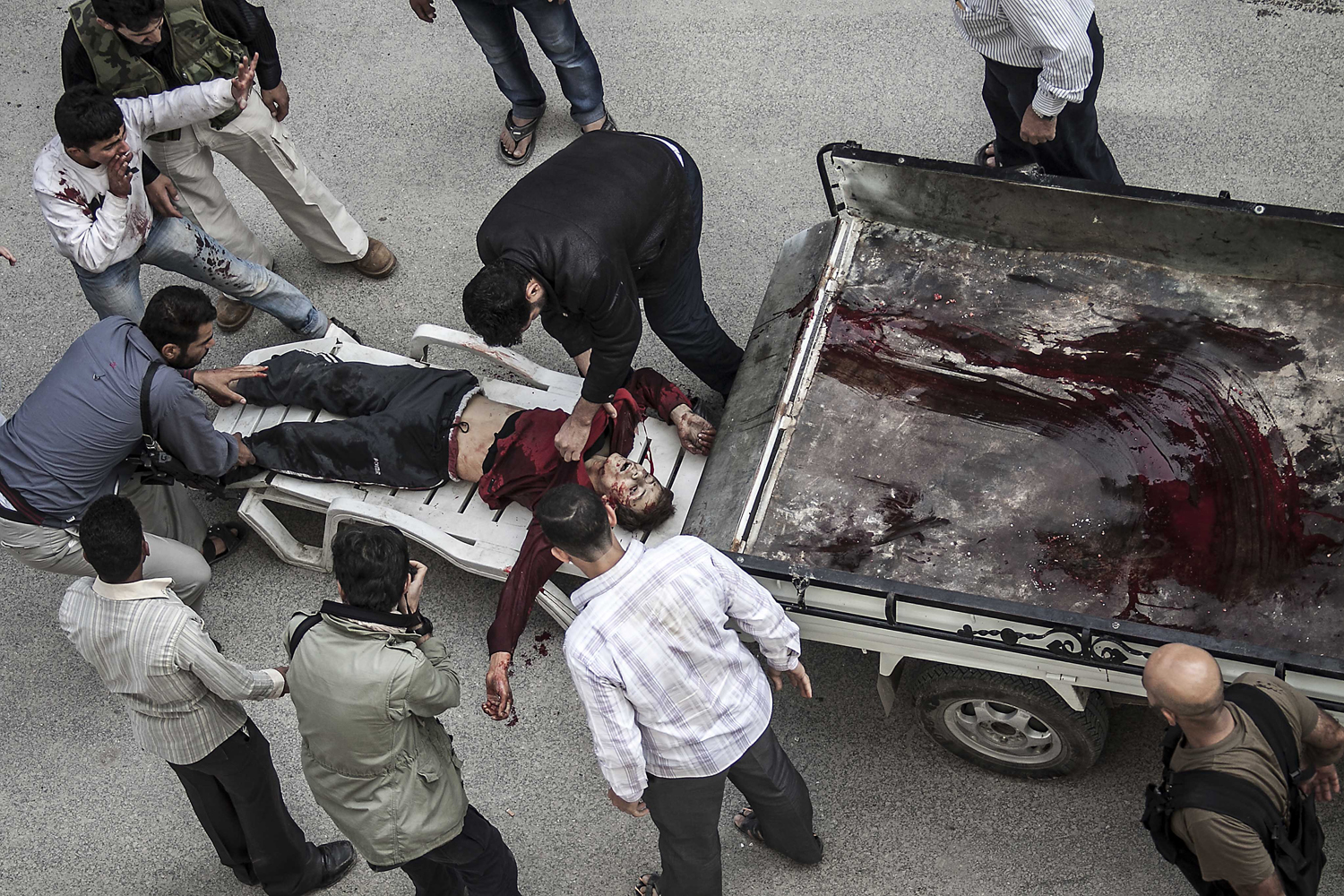 Image: Oct. 23, 2012. Syrian residents carry the lifeless body of a boy killed by an artillery shell that landed near a bakery, in front of a hospital in Aleppo, Syria.