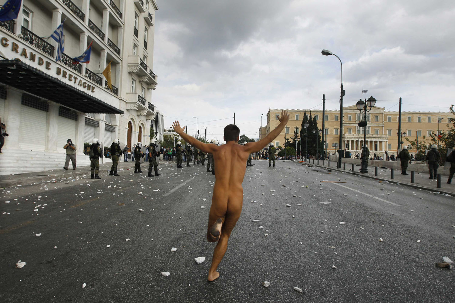 Oct. 9, 2012. A naked protester runs past the parliament in Syntagma Square in Athens during a violent protest against the visit of Germany's Chancellor Angela Merkel.