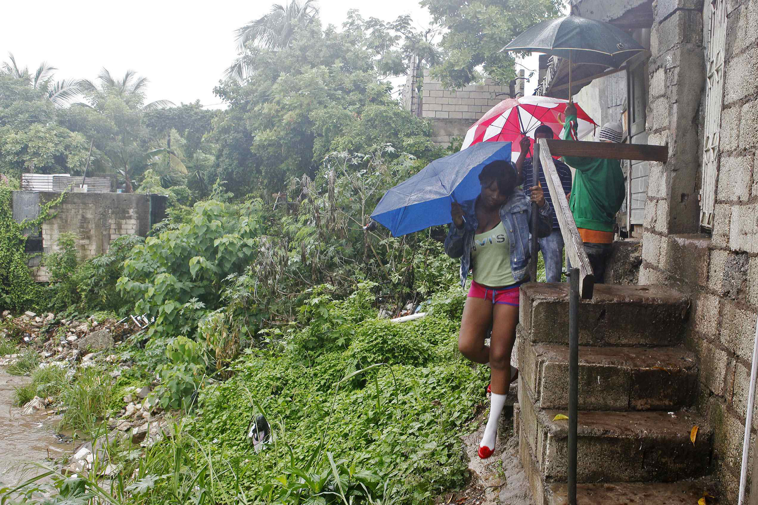 Image: Oct. 24, 2012. Jamaicans shelter themselves from the rain of approaching Hurricane Sandy as they walk along Sandy Park Gully in Kingston.