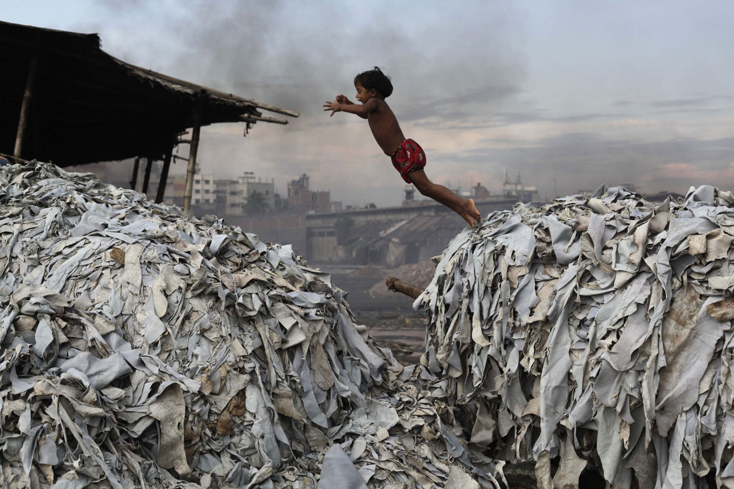 Oct. 9, 2012. A child jumps on the waste products that are used to make poultry feed as she plays in a tannery at Hazaribagh in Dhaka, Bangladesh. Luxury leather goods sold across the world are produced in a slum area of Bangladesh's capital where workers, including children, are exposed to hazardous chemicals and often injured in horrific accidents, according to a study released on Tuesday.