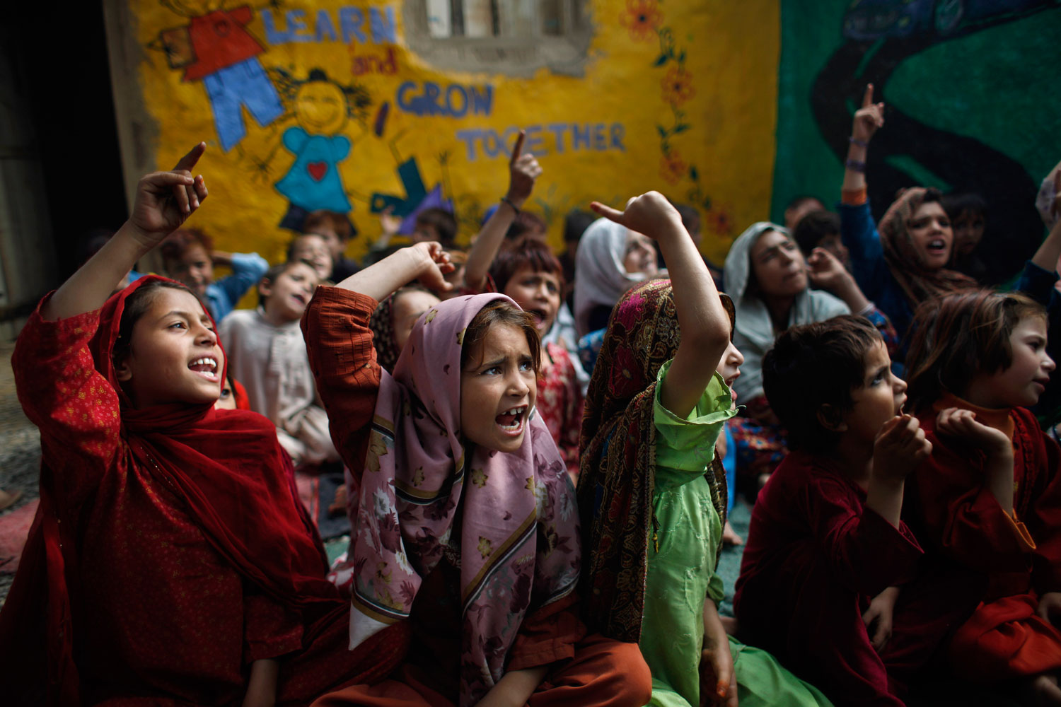 Image: Oct. 19, 2012. Pakistani students, displaced along with their families from Pakistan's tribal areas due to fighting between militants and the army, chant a song with their teacher, not pictured, during their daily school in a poor neighborhood on the outskirts of Islamabad.