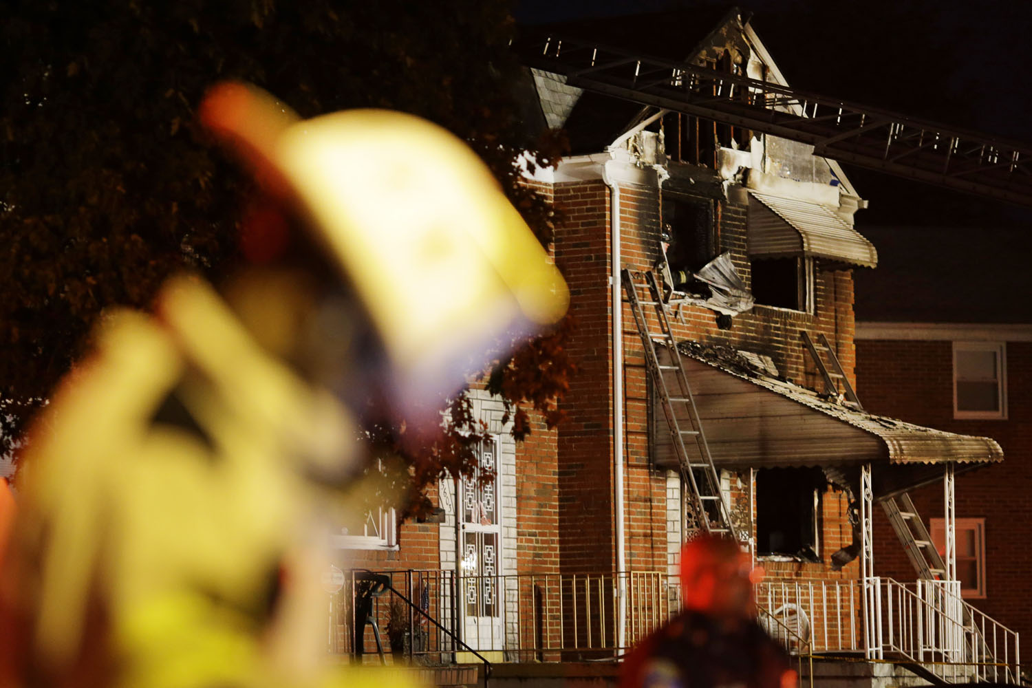 Oct. 11, 2012. Officials stand in front of a fire-damaged house in Baltimore, where an early morning fire claimed the lives of an adult and four children.