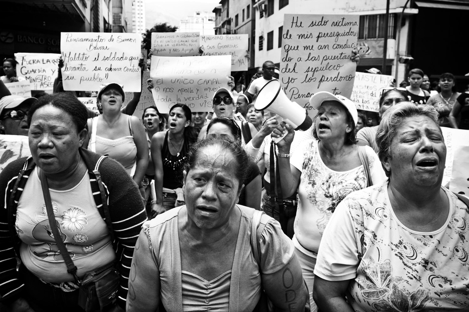 image: Relatives of "El Rodeo" prison inmates rally in front of the Ministry of Internal Affairs to protest for living conditions of the prisoners. Due to corruption and lacking infrastructure, the inmates are often responsible for providing for their own basic needs. Despite the efforts of the government to reorganize the penitentary system, which has been neglected for decades, the prevalence of corruption, drug trafficking and weapon smuggling inside the jails grows yearly.