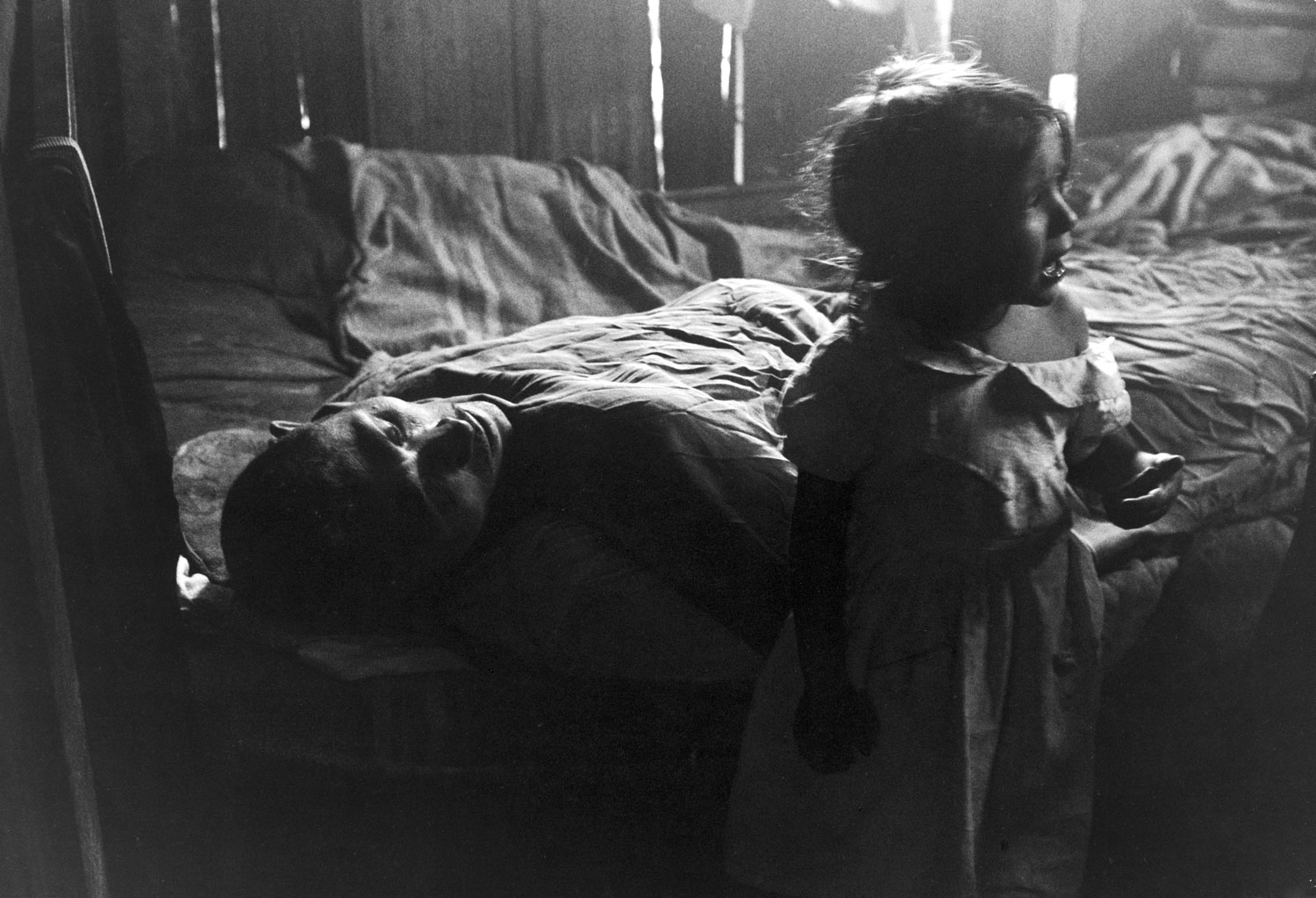 In the shadowy slum world into which she was born in Rio de Janeiro, 3-year old Isabel da Silva cries to herself after vainly seeking comfort from her exhausted father, Jose.