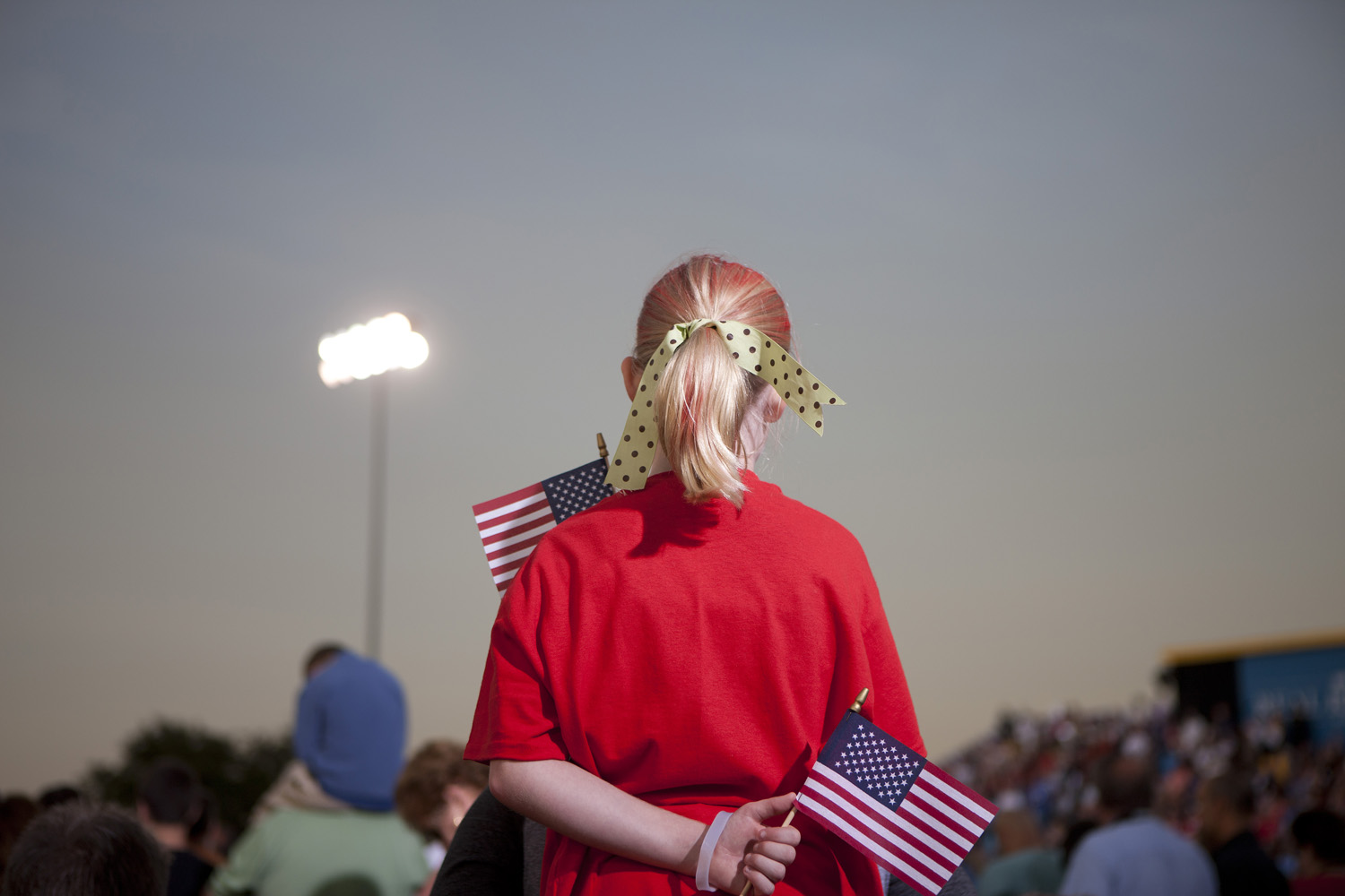 Image: Oct. 27, 2012. A red-clad Romney supporter clutches two American flags during a rally at a football stadium in Land O’ Lakes, Fla.