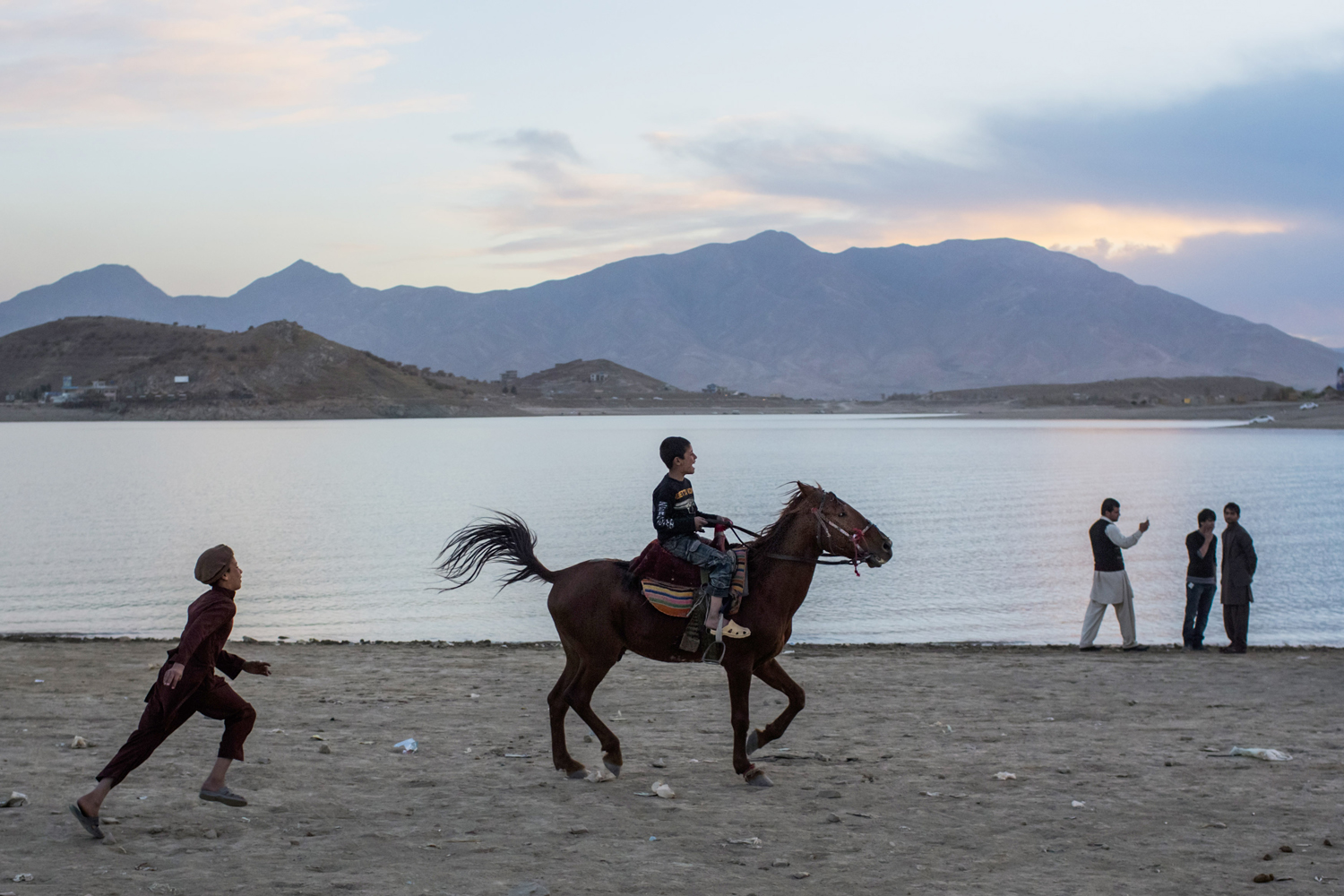 Image: Nov. 9, 2012. An Afghan boy chases his friend riding a horse at the Qargha Lake in Kabul.