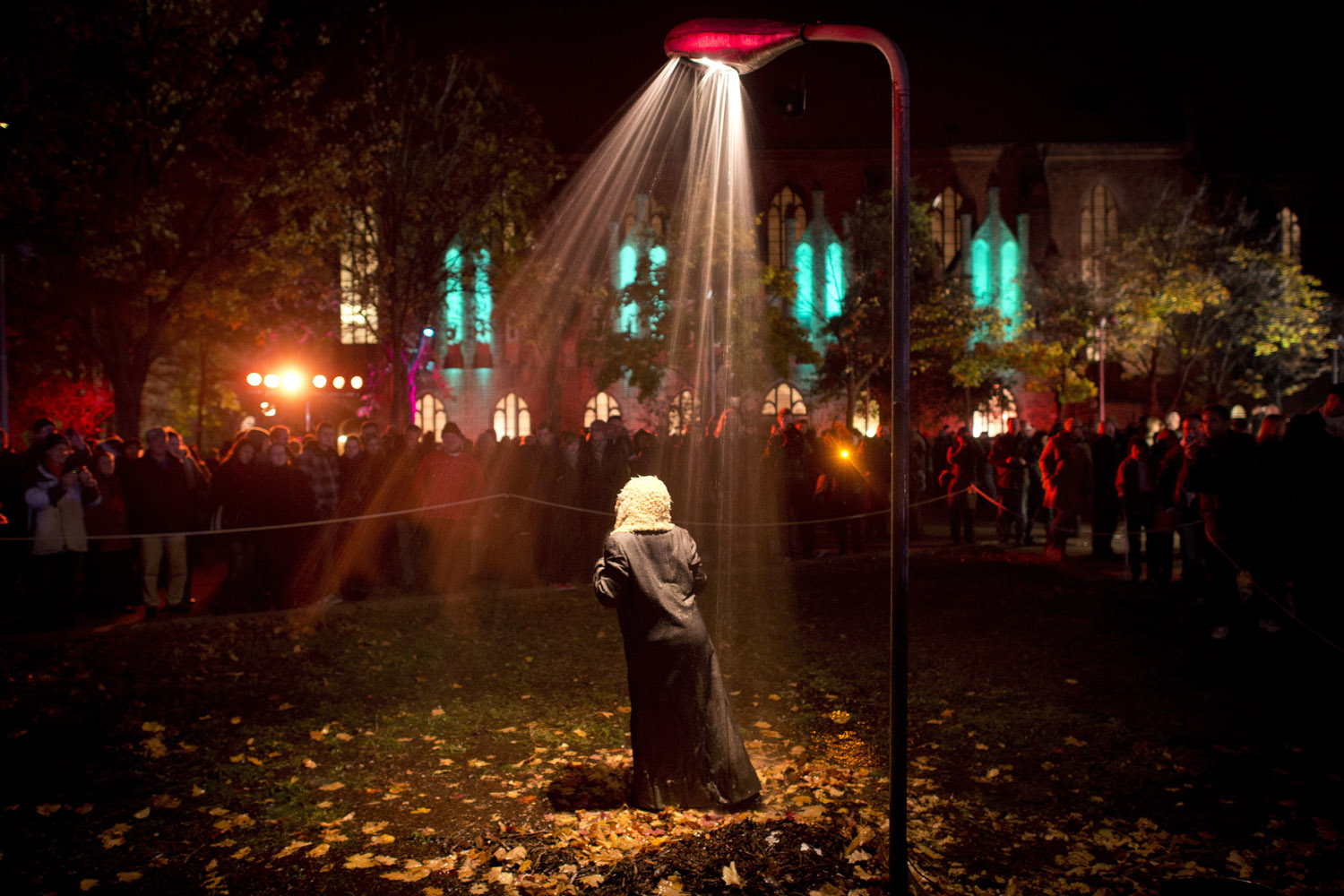 Image: Oct. 28, 2012. A performer stands in a streetlight shower as part of an installation to celebrate the city's 775th anniversary in Berlin's Nikolai Quarter.
