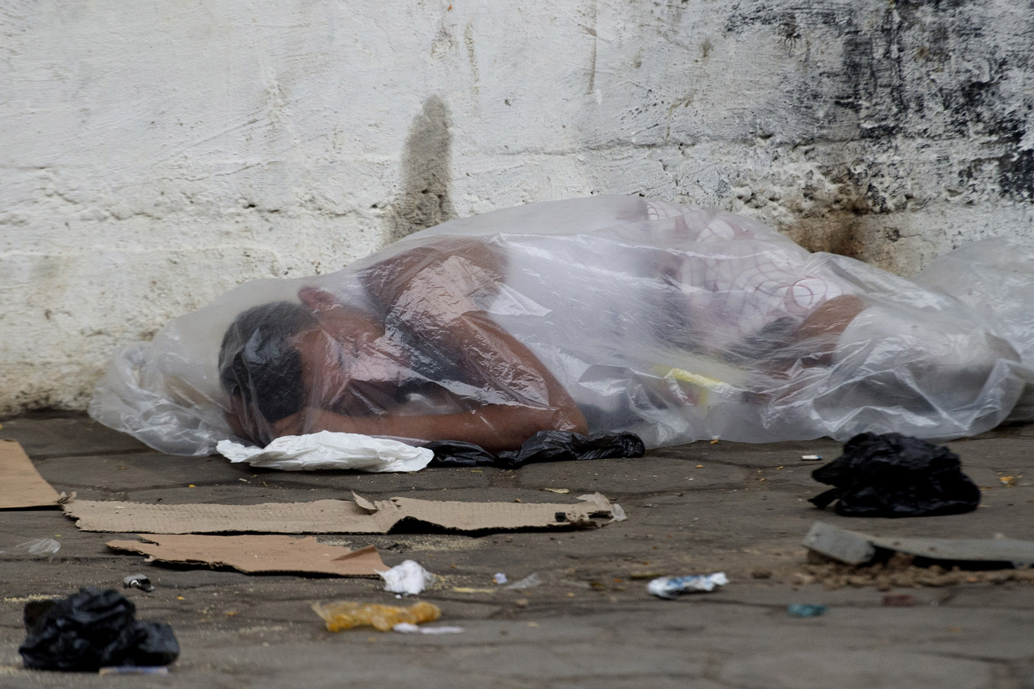 Image: Oct. 26, 2012. A crack addict sleeps on the sidewalk covered with a plastic sheet next to Parque Uniao slum before a social workers and police joint operation to take addicts out of the streets, in Rio de Janeiro.