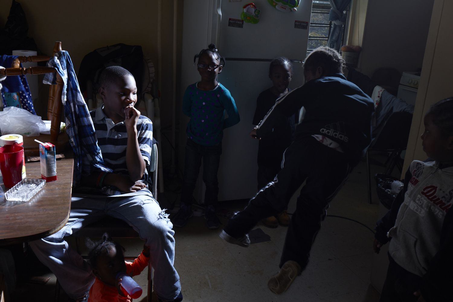 Image: Nov. 10, 2012. Kingsley Ihim, 12, Markeya Ihim, 15 mos., Jazzamia Ihim, 7, Martin Ihim, 4, and Shaun Ihim, 5, watch as Kebion, 6, practices his karate moves in the family’s 4th floor kitchen in the Redfern Houses of Rockaway, N.Y.