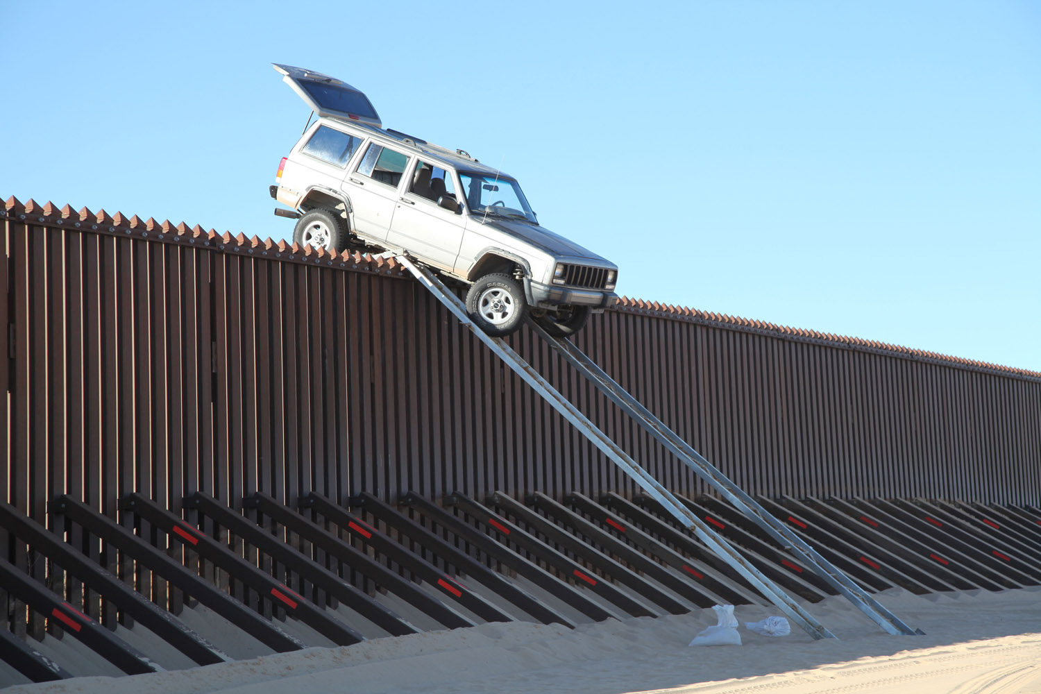Image: Oct. 31, 2012. Suspected smugglers attempting to drive a silver Jeep Cherokee over the U.S.-Mexico border fence is stuck at the top of a makeshift ramp in Yuma, Ariz.