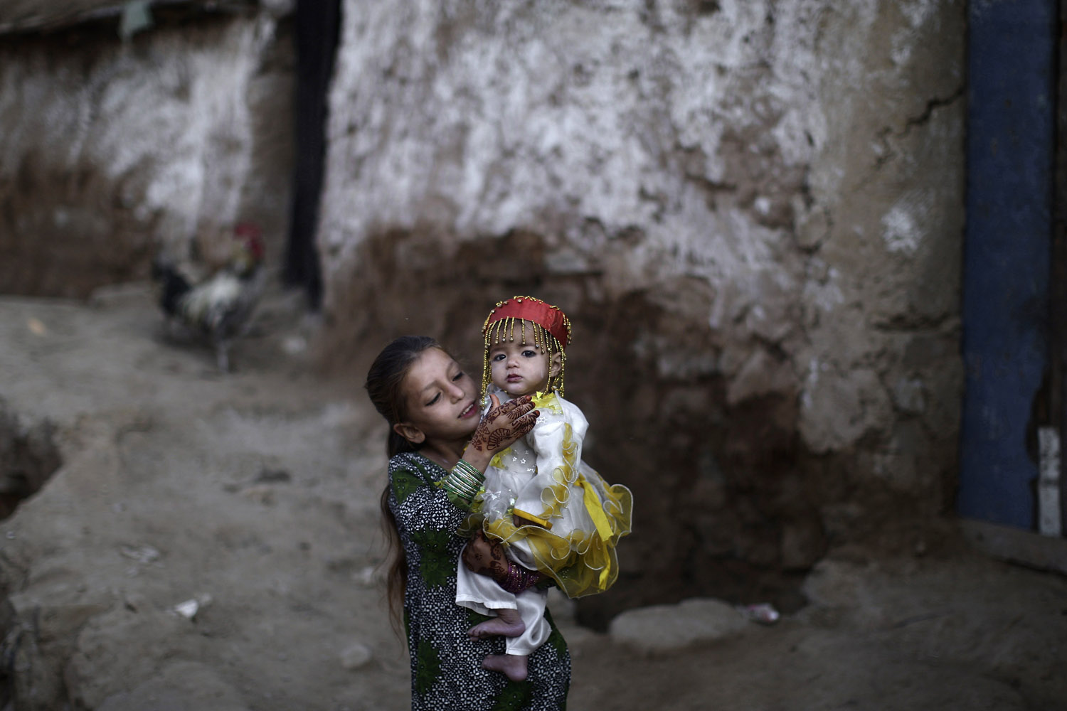 Image: Oct. 27, 2012. Afghan refugee girl Parveen Bashir, 6, plays with her sister Shaheen, 1, dressed in new clothes, while celebrating the first day of the Muslim holiday of Eid al-Adha, or "Feast of Sacrifice", on the outskirts of Islamabad.
