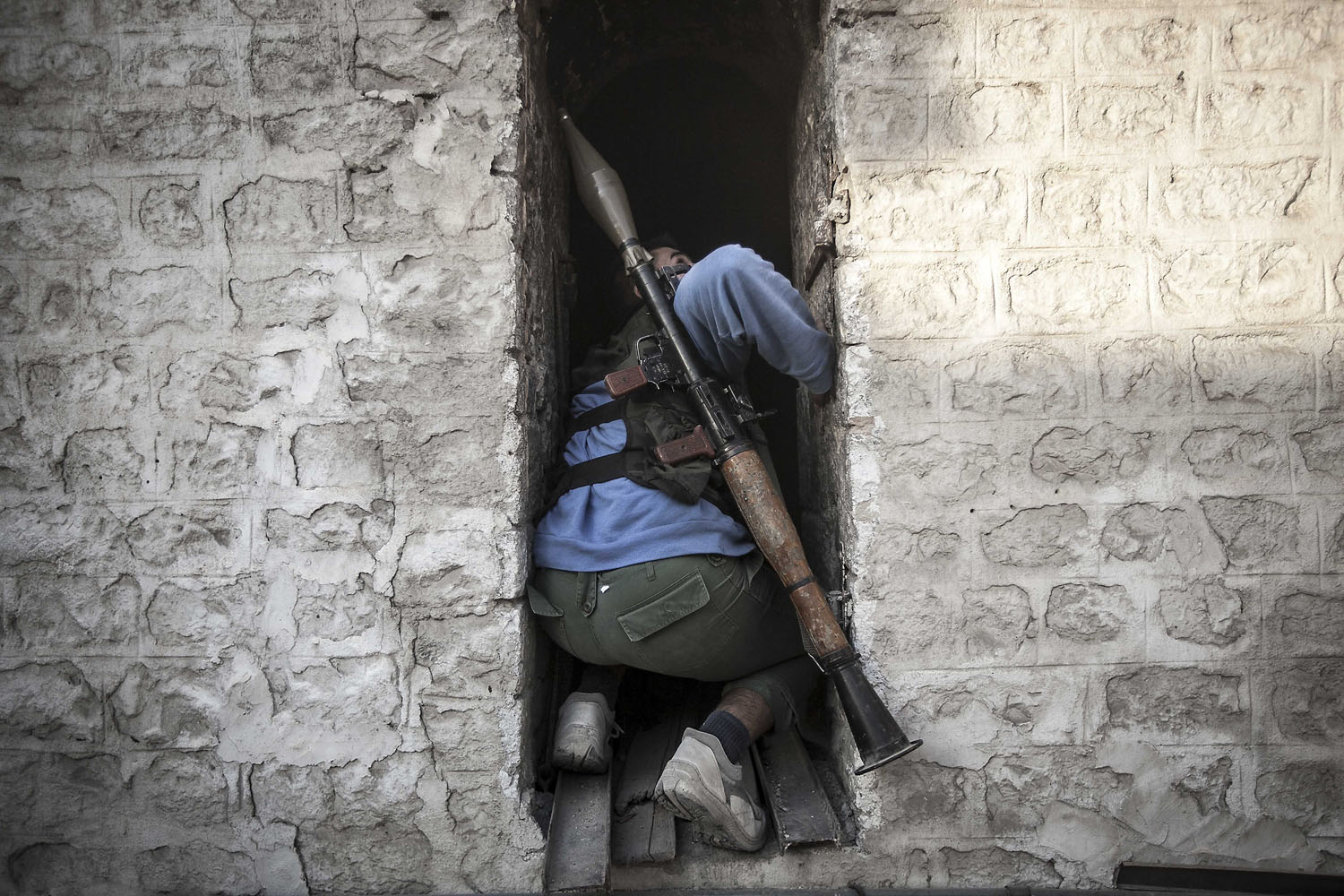 Image: Nov. 3, 2012. A rebel fighter takes cover as he looks up at a warplane attacking rebel positions during heavy clashes between rebel fighters and the Syrian army.