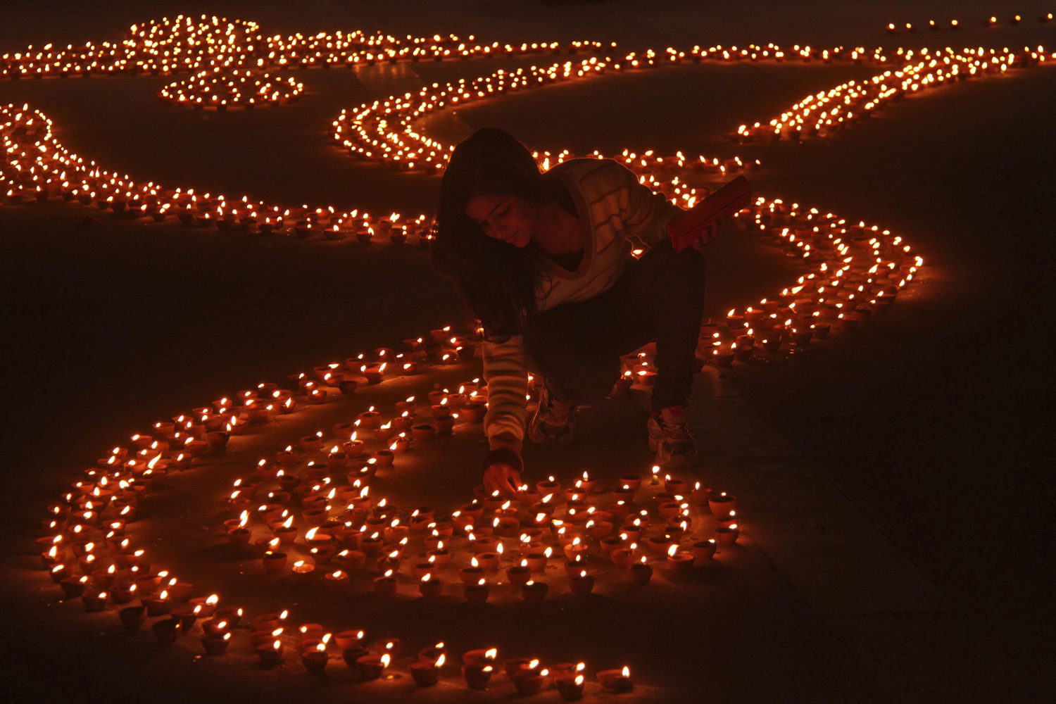 Image: Nov. 12, 2012. A girl lights earthen lamps in a formation to form the shape of the Hindu god Ganesh, the deity of prosperity, on the eve of Diwali, the Hindu festival of lights, in the northern Indian city of Chandigarh.