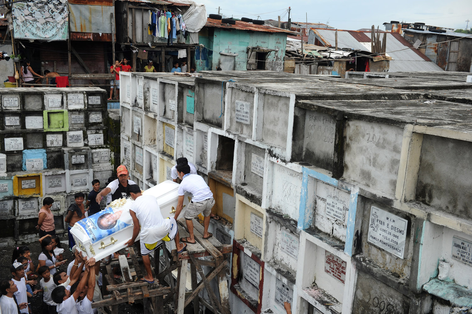 Image: Oct. 28, 2012. Workers place a coffin in a grave as relatives of the deceased watch at the Navotas Municipal Cemetery in Manila. Millions of Filipinos will soon flock to cemeteries around the country to visit departed relatives and loved ones as they mark All Saints Day and All Souls Day.