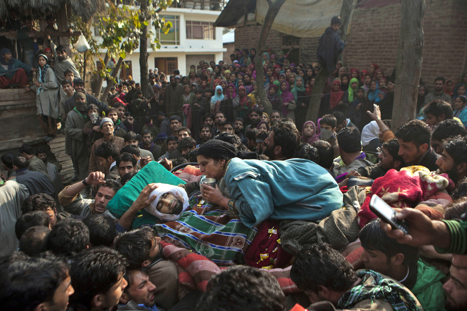 Image: Nov. 14, 2012. The mother of Shabir Ahmed Mir, a suspected militant of Lashkar-e-Taiba, holds a glass of milk as she clings to the bed carrying the body of her son during his funeral procession in Chingam, India.