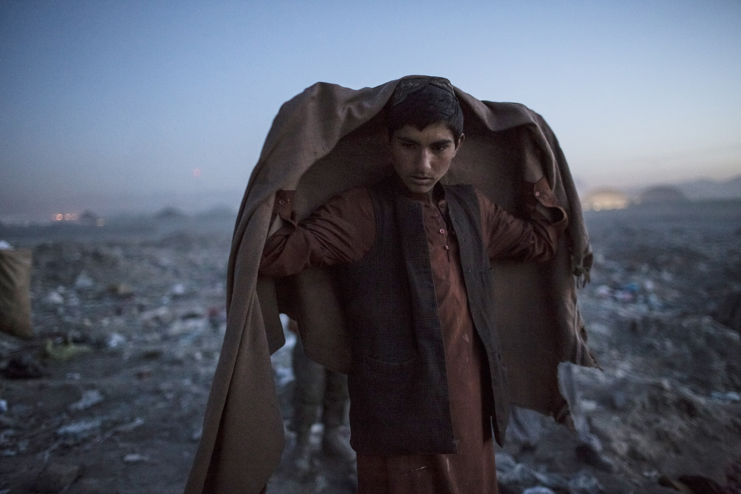 Image: Nov. 14, 2012. An Afghan Pashtun boy, who said he was forced from the troubled province of Baglan due to threats from the Taliban, winds up his day after scavenging for recyclables at a garbage dump site in Kabul.