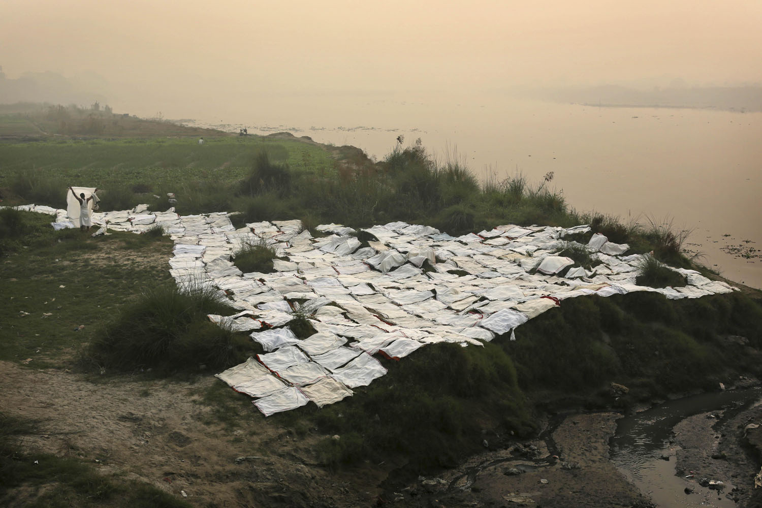 Image: Nov. 6, 2012. An Indian man dries laundry on the polluted Yamuna River on a hazy morning in New Delhi.