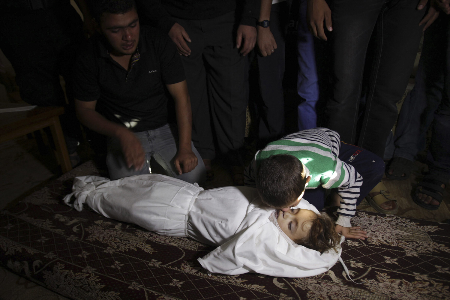 Image: Nov. 15, 2012. The brother of Palestinian boy Walid al-Abadlah, who according to hospital officials was killed in an Israeli air strike, kisses his body during his funeral in Khan Younis in the southern Gaza Strip.